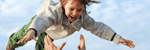 Fotografija nasmejana otroka, ki ga nekdo meče v zrak